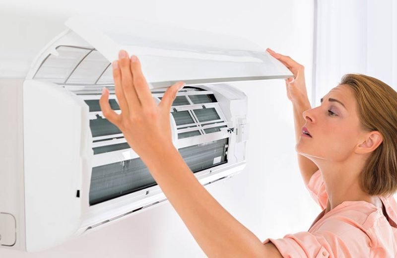 woman checking filters on air conditioner